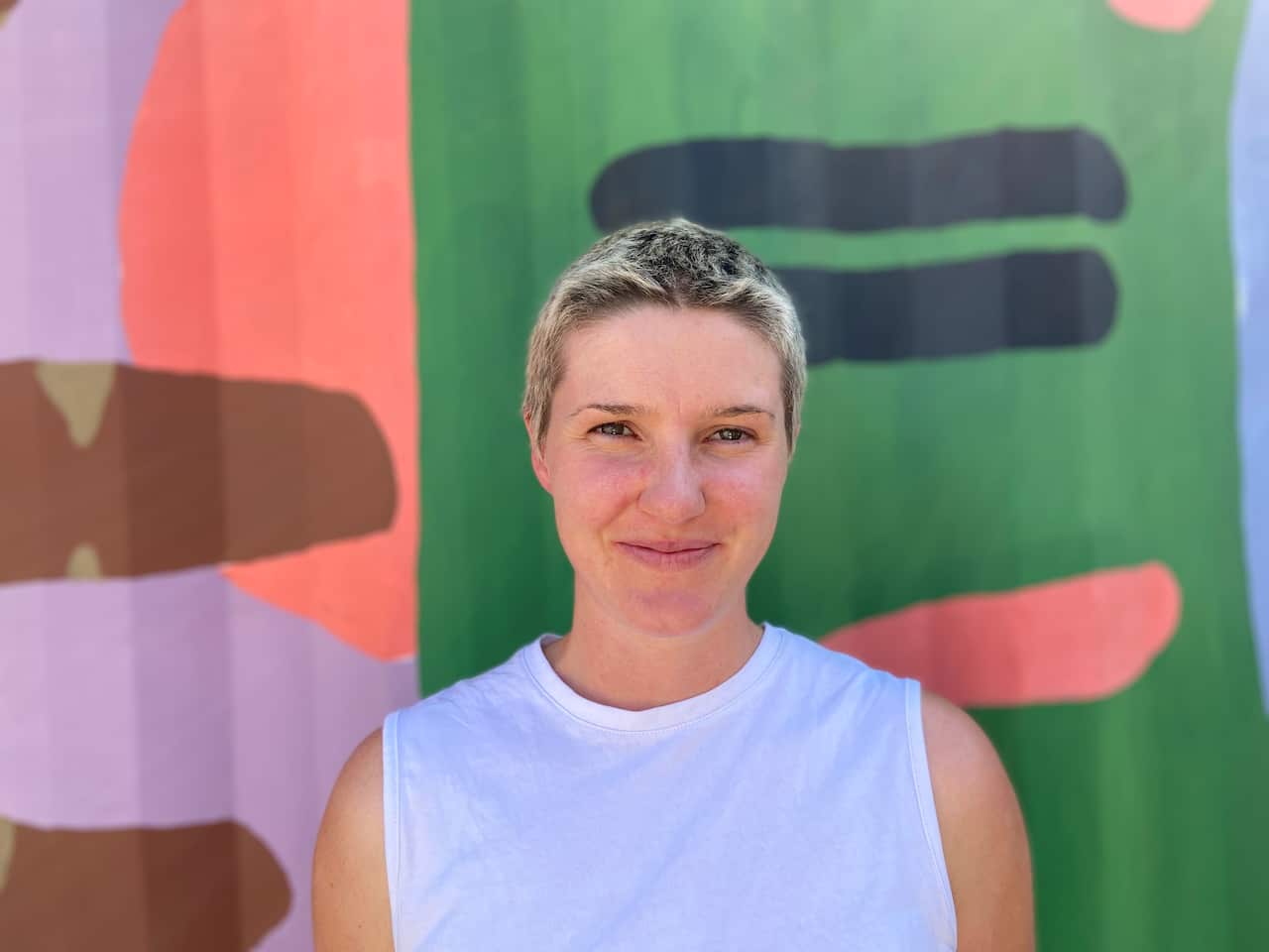 A woman with short hair wearing a white shirt smiling.