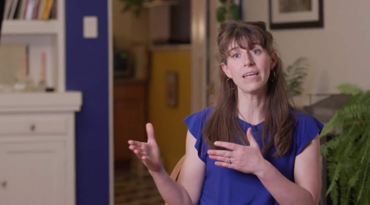 A woman talks to camera. 