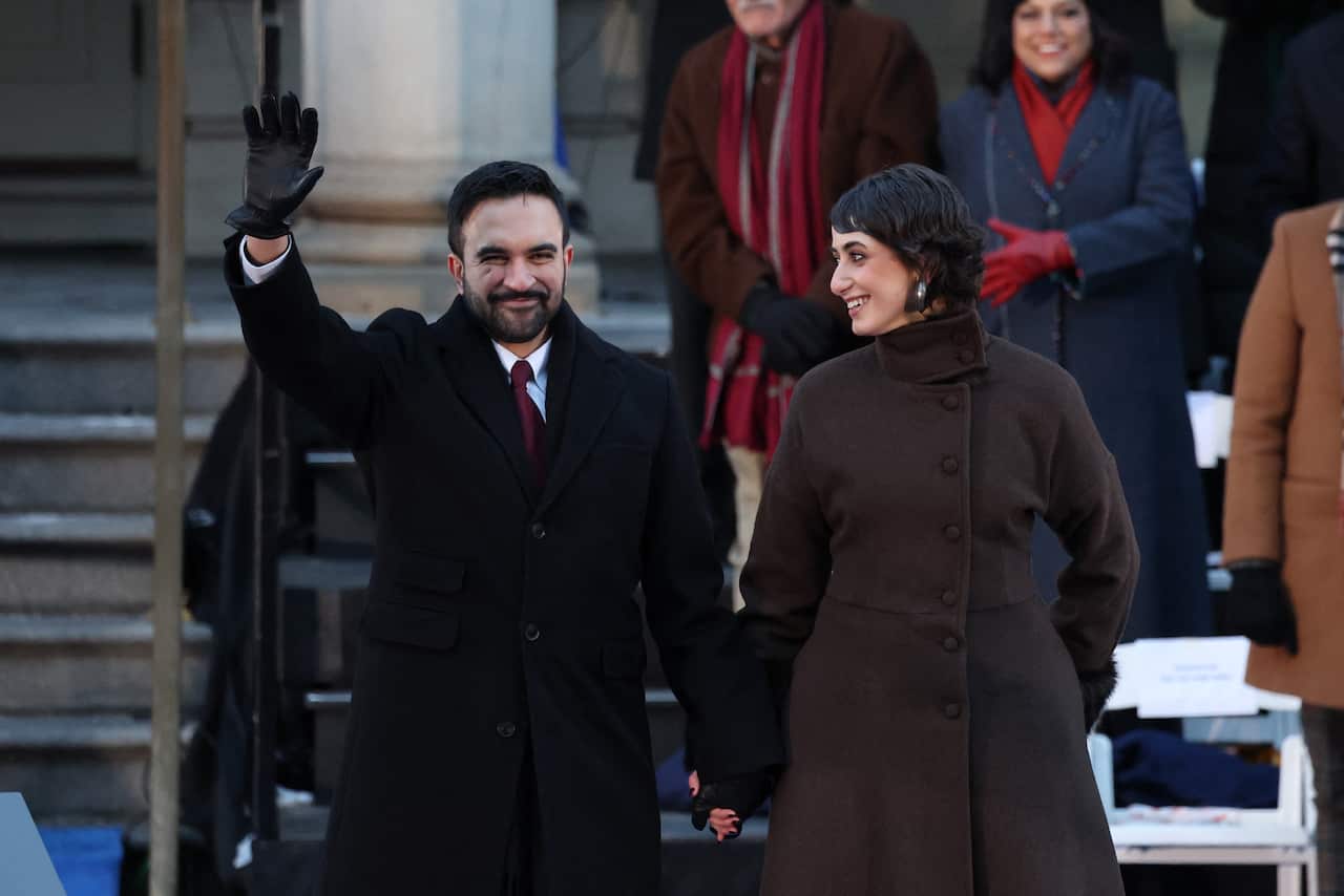 A man waves while holding hands with a woman