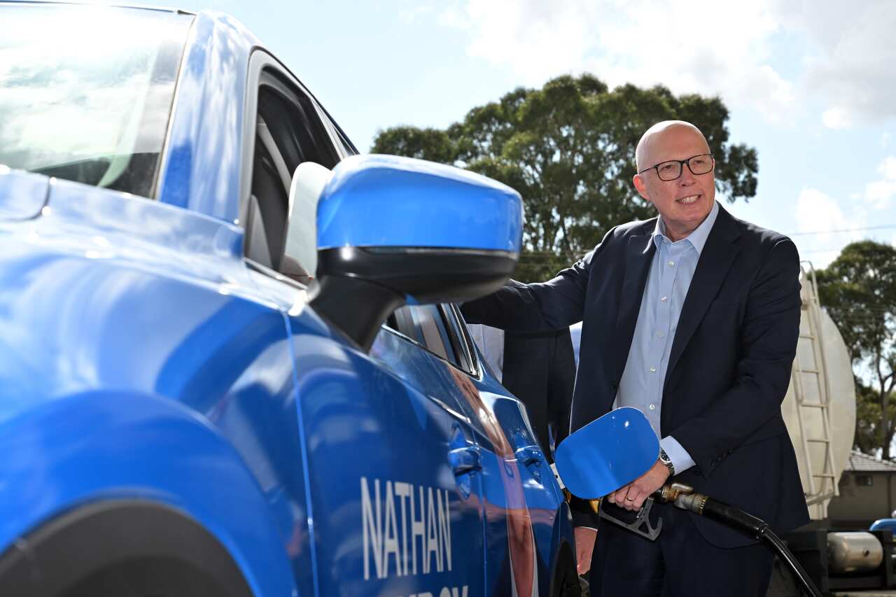 Peter Dutton fills up a car with petrol. 