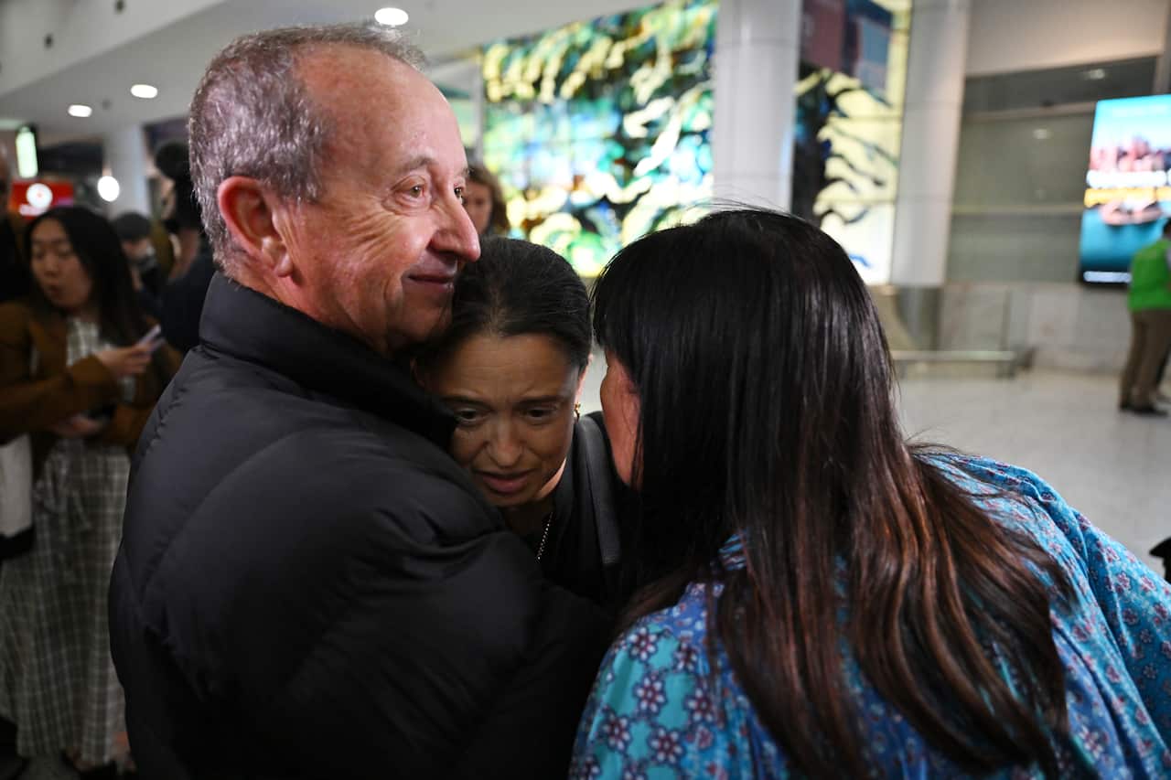 A man looks emotional as he hugs a younger woman at the arrivals hall of Sydney airport.