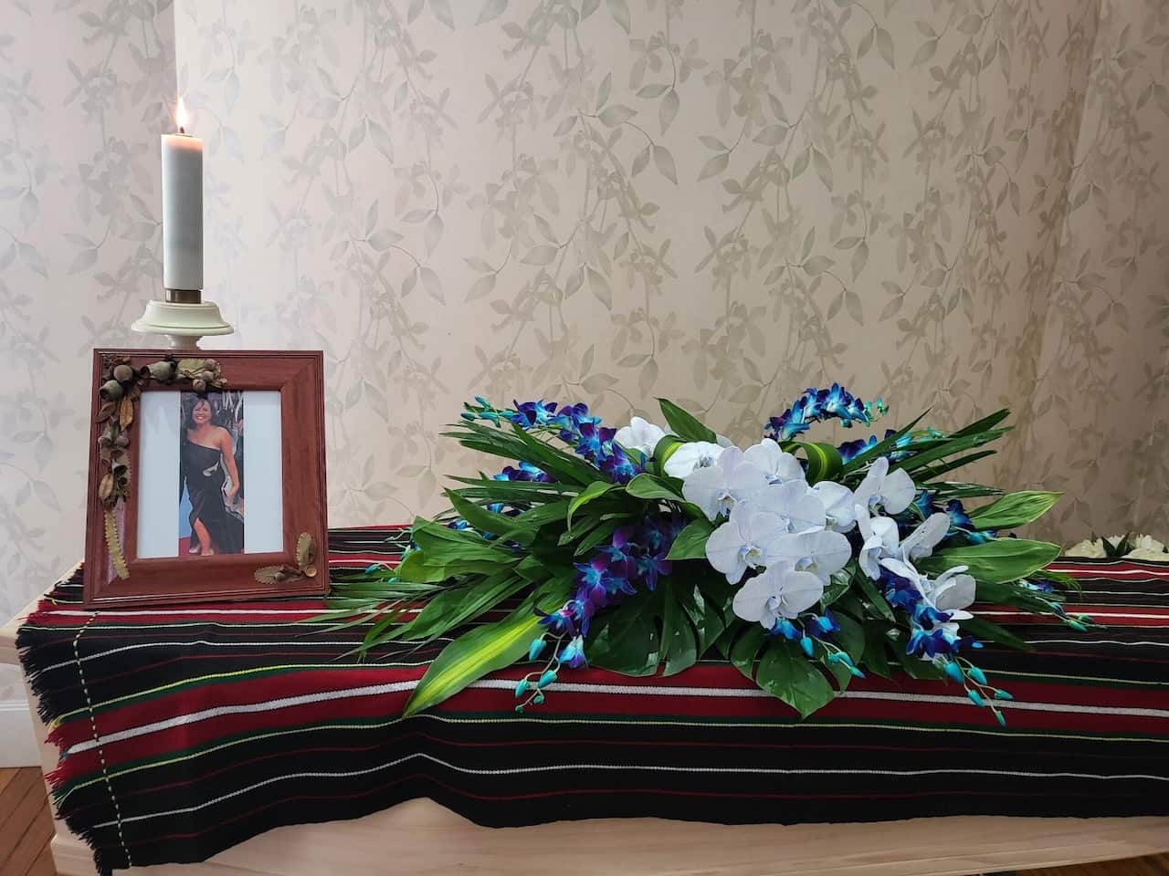 A casket with flowers and a picture of a woman on it. 