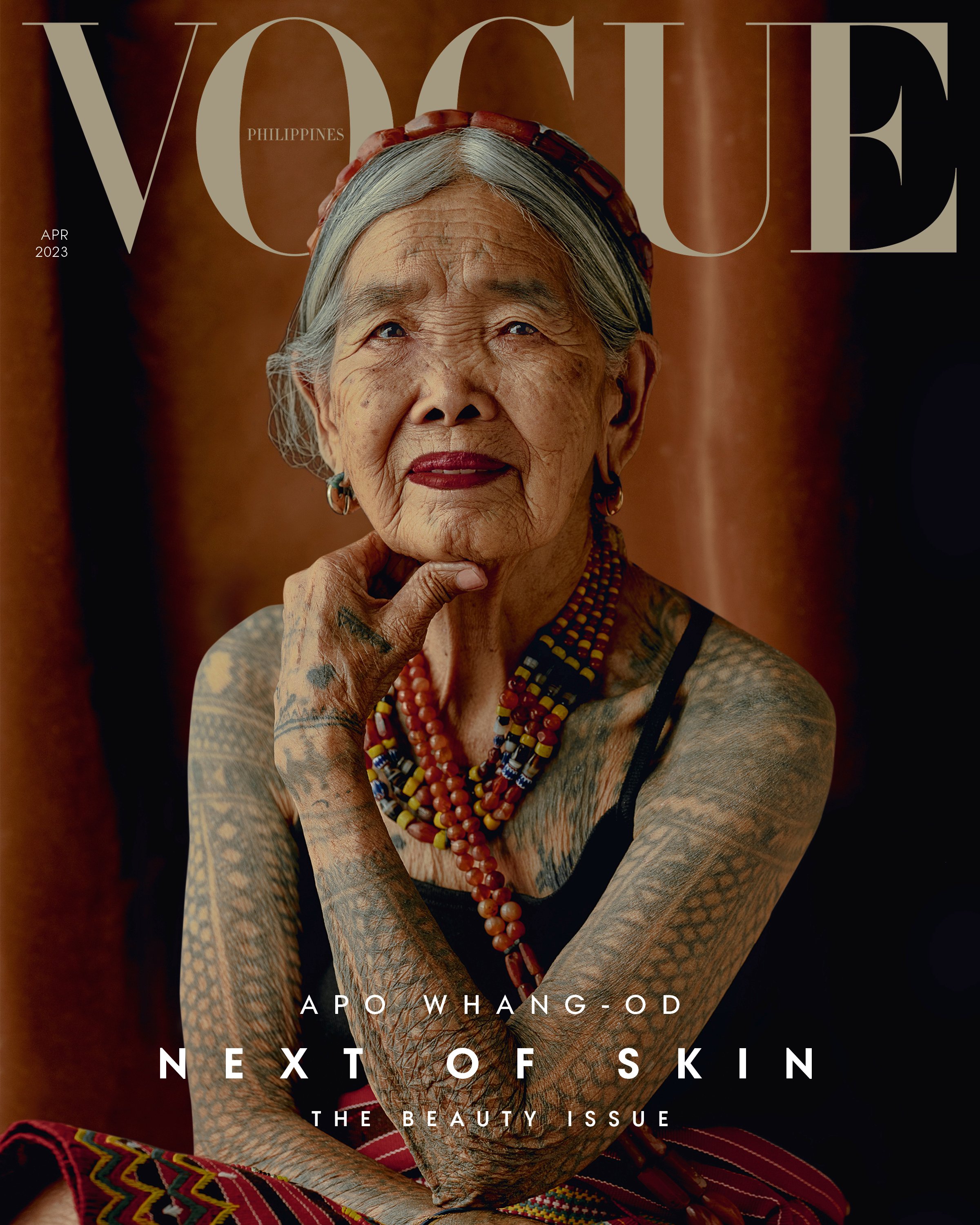 Cover of a Vogue magazine featuring an older lady posing with her arms covered in tattoos 
