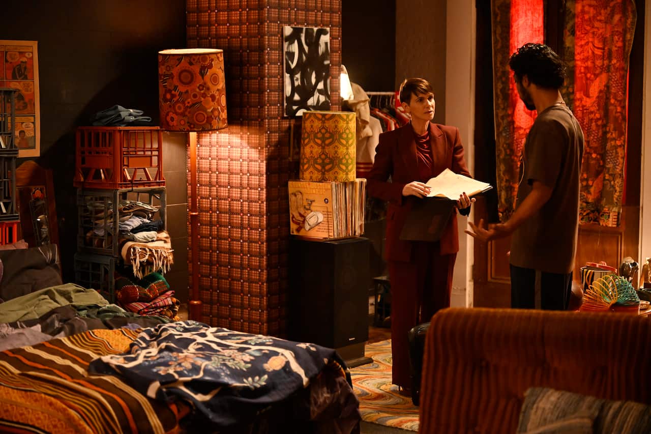 A man and a woman standing and talking to each other in a bedroom.
