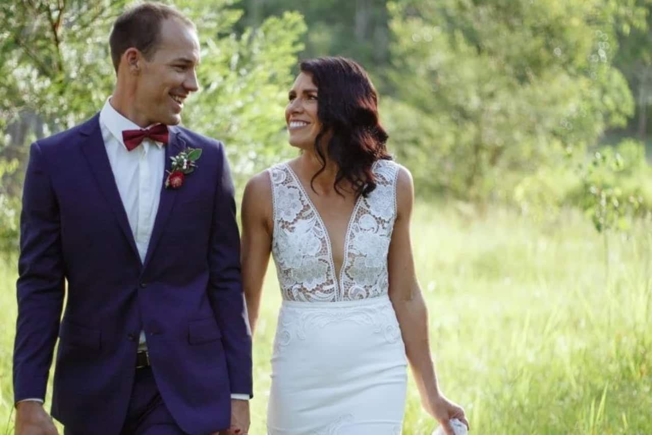 Man and woman in wedding outfits standing outside smiling
