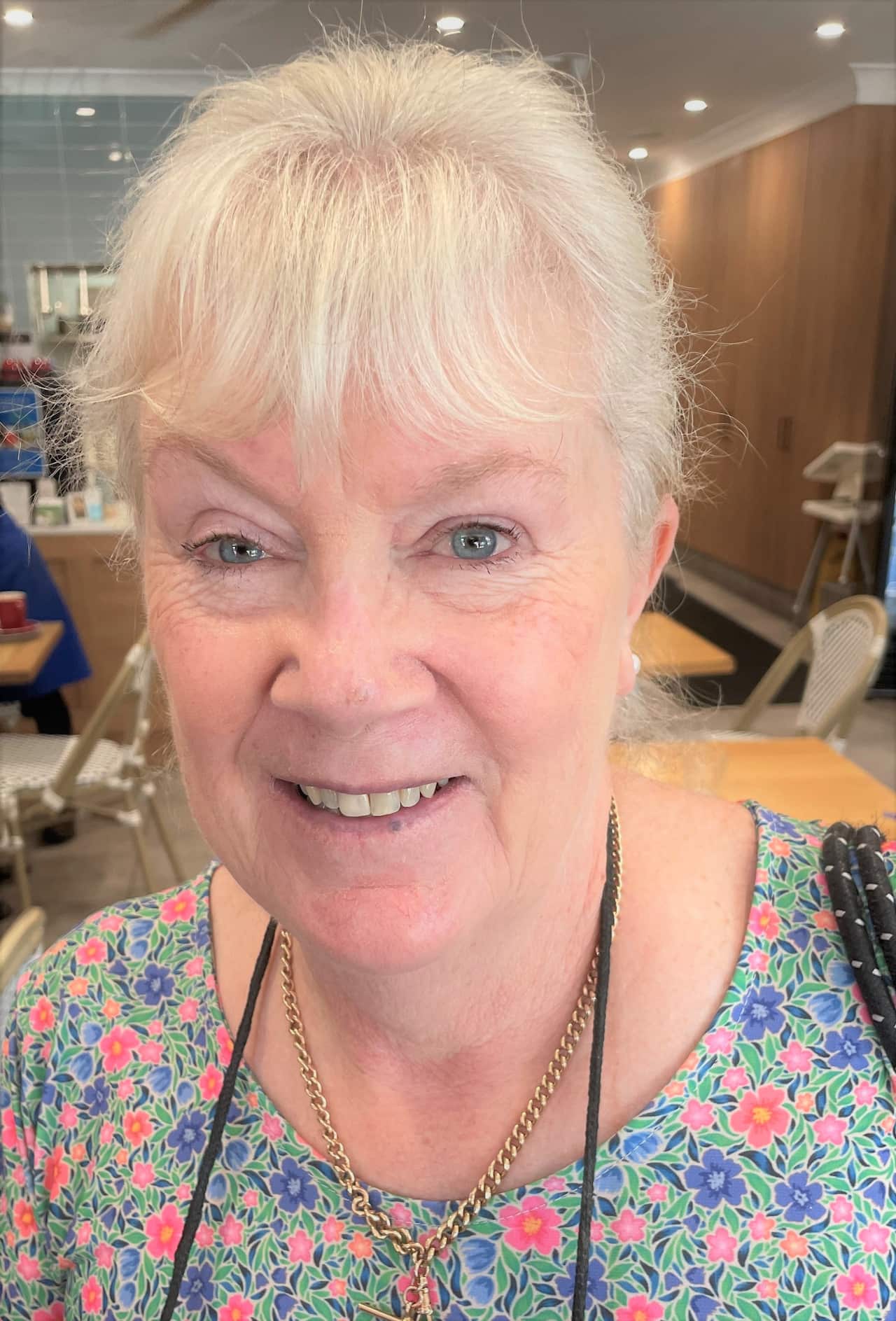 An older woman with grey hair wearing a floral top.