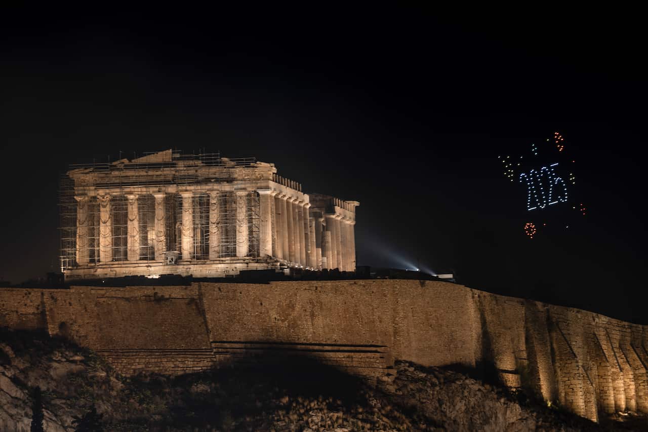 Drones form '2025' in the sky next to an ancient temple on a hill. 