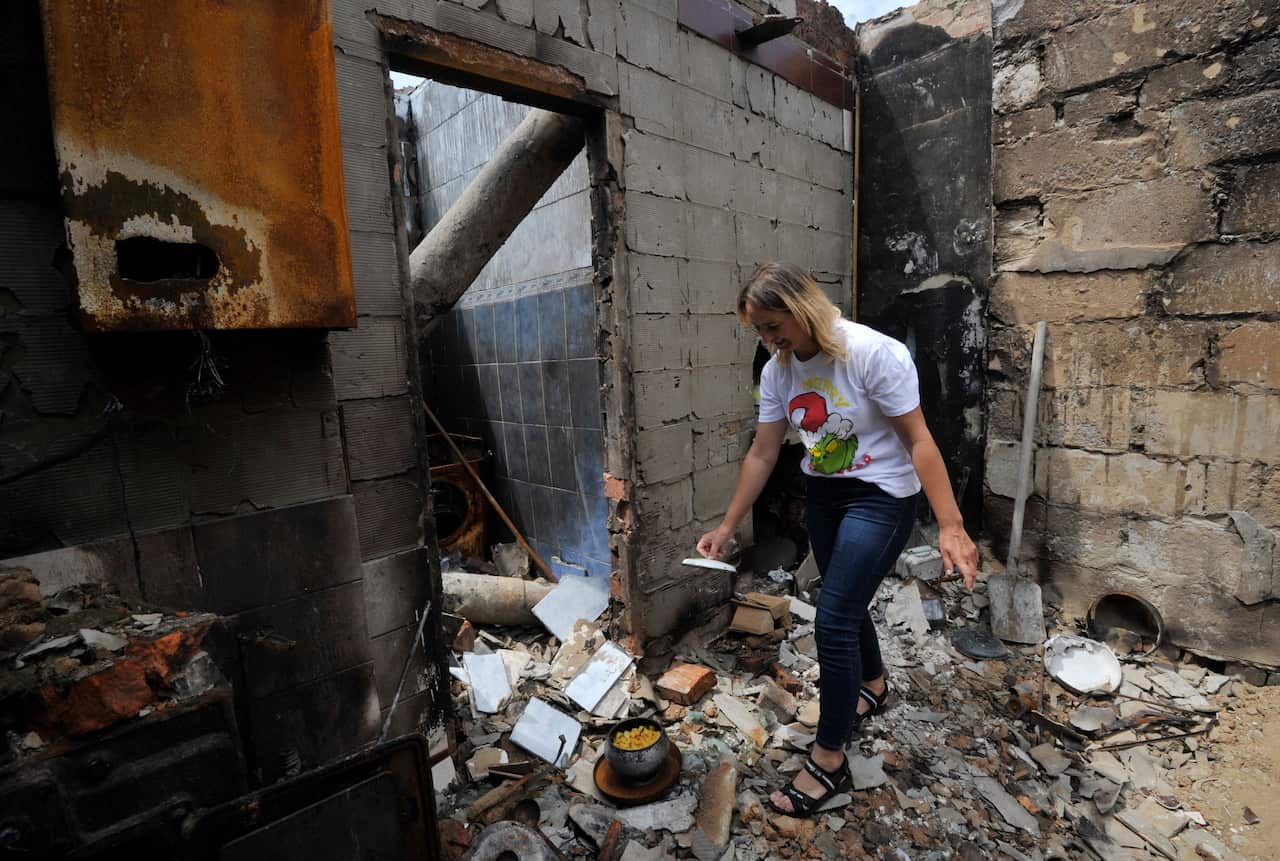 A woman cooks in a house in ruins