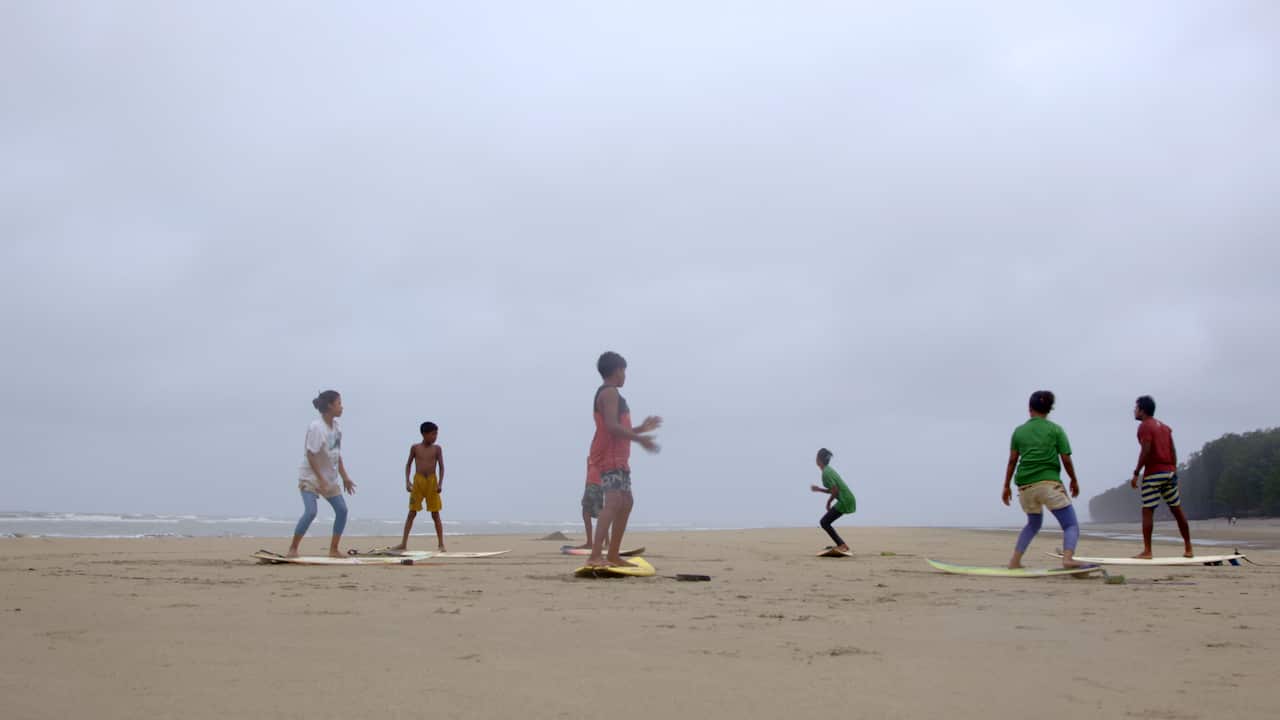 A group of people standing on surfboards on the beach.