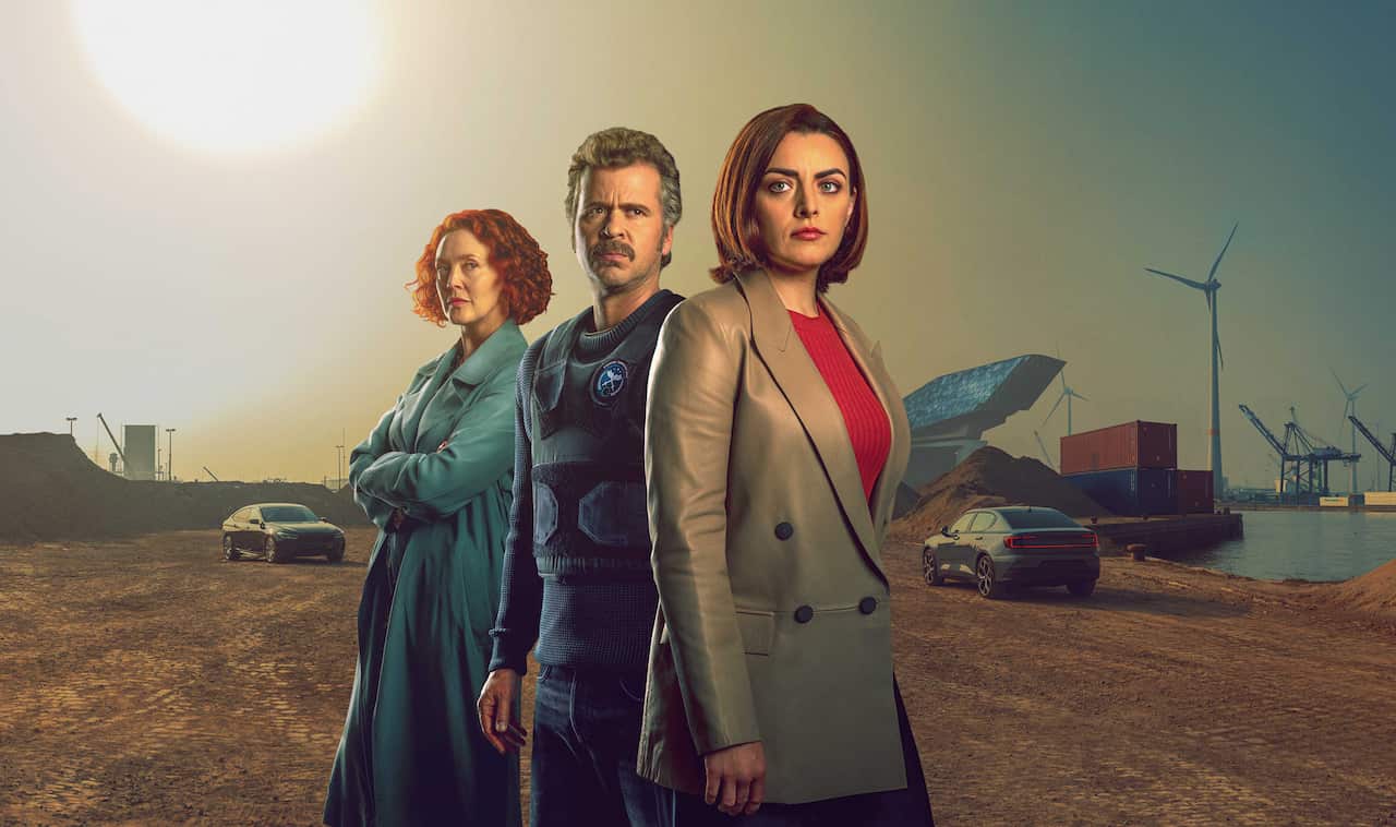 2 women and a man stand at the edge of a port