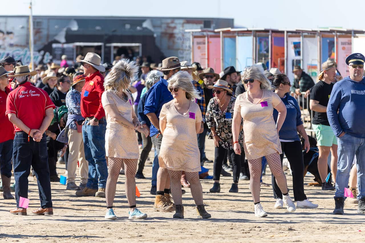 Group of people in costumes standing in the desert.