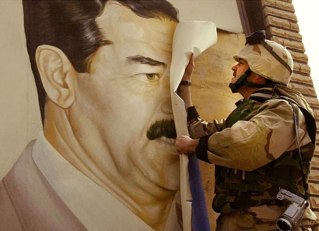  A US marine pulls down a poster of former Iraqi president Saddam Hussein.