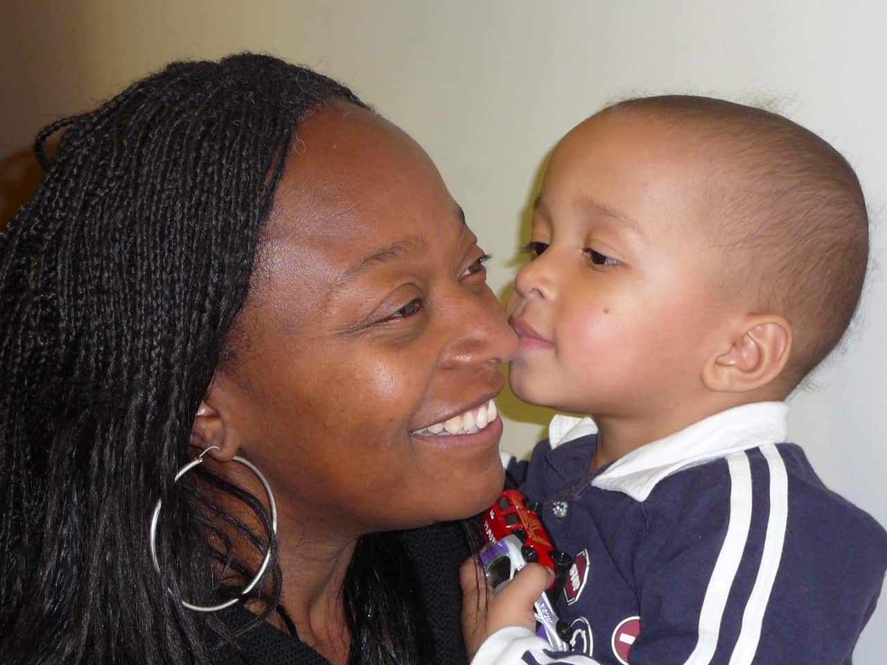 Woman holding her toddler son and smiling. 