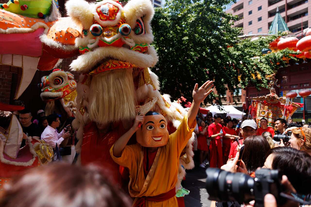 People watch as a person wearing a mask, and others in dragon costumes dance.