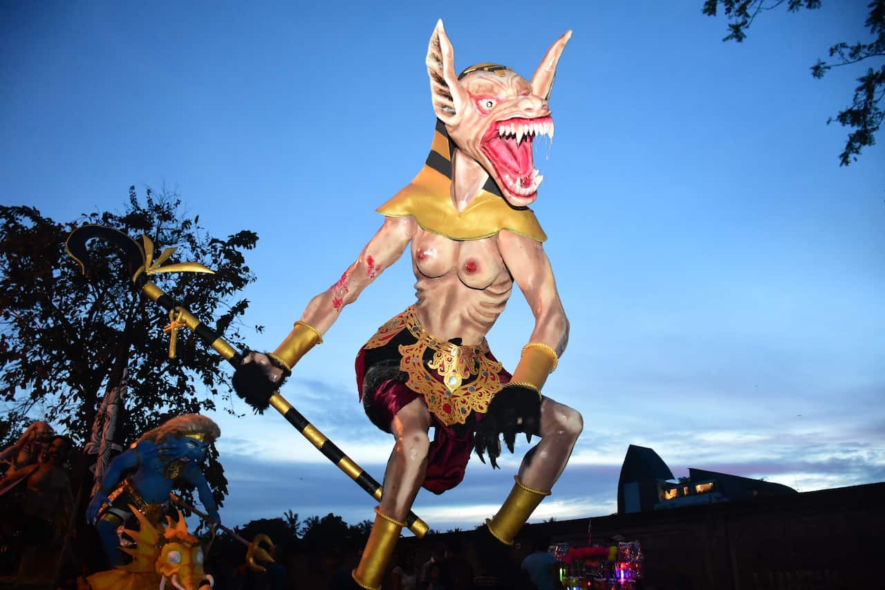 A bare chested monster with large teeth and ears, wearing a skirt and holding a staff.