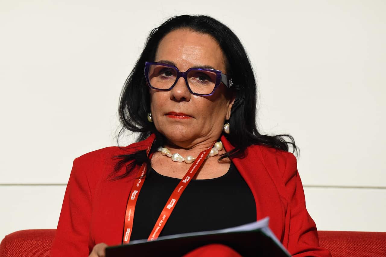 A woman wearing glasses looks at the camera