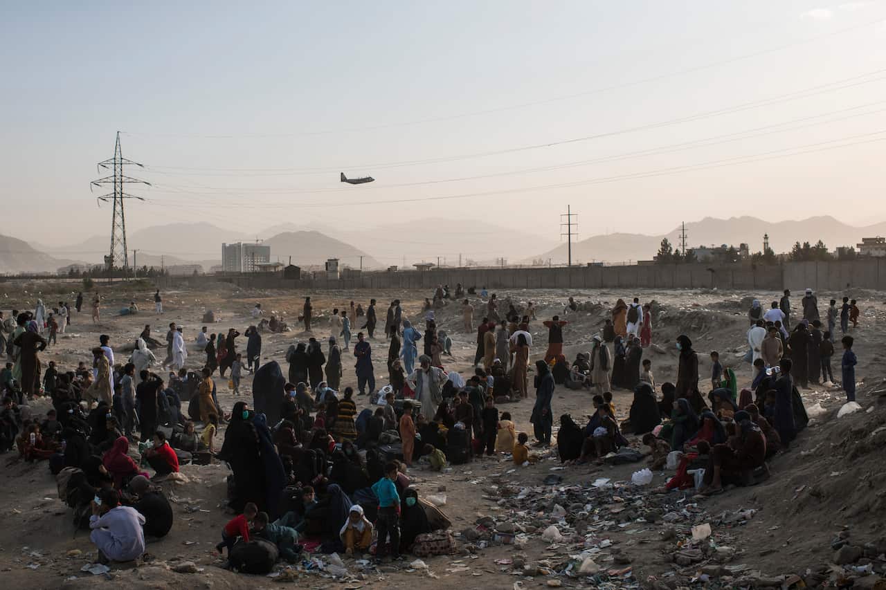  A crowd of people waiting in a dusty field.
