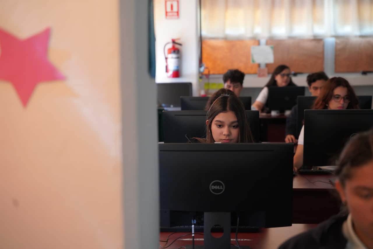Students looking at their computers in a classroom. 