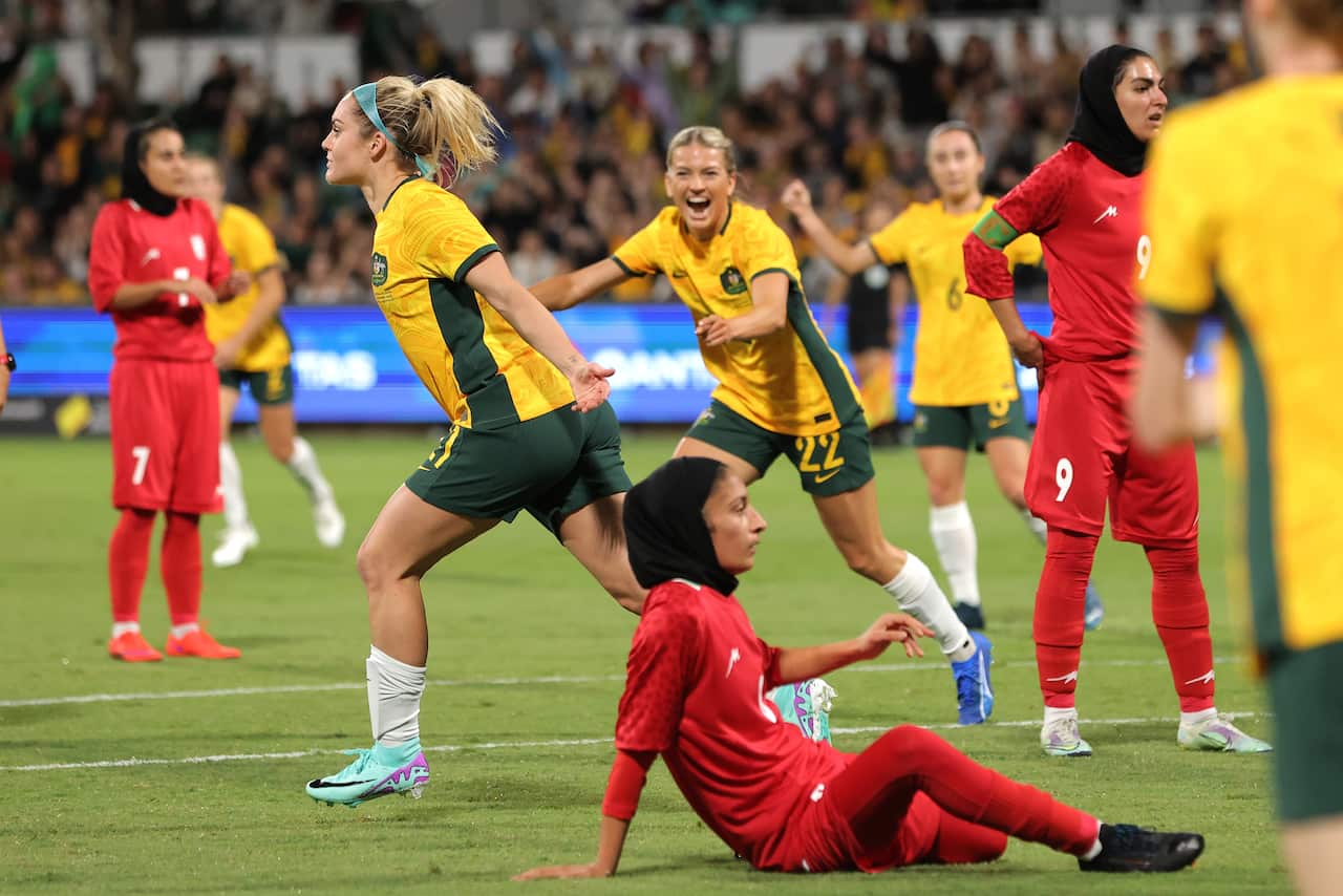 Women in football uniforms celebrate a goal being scored.