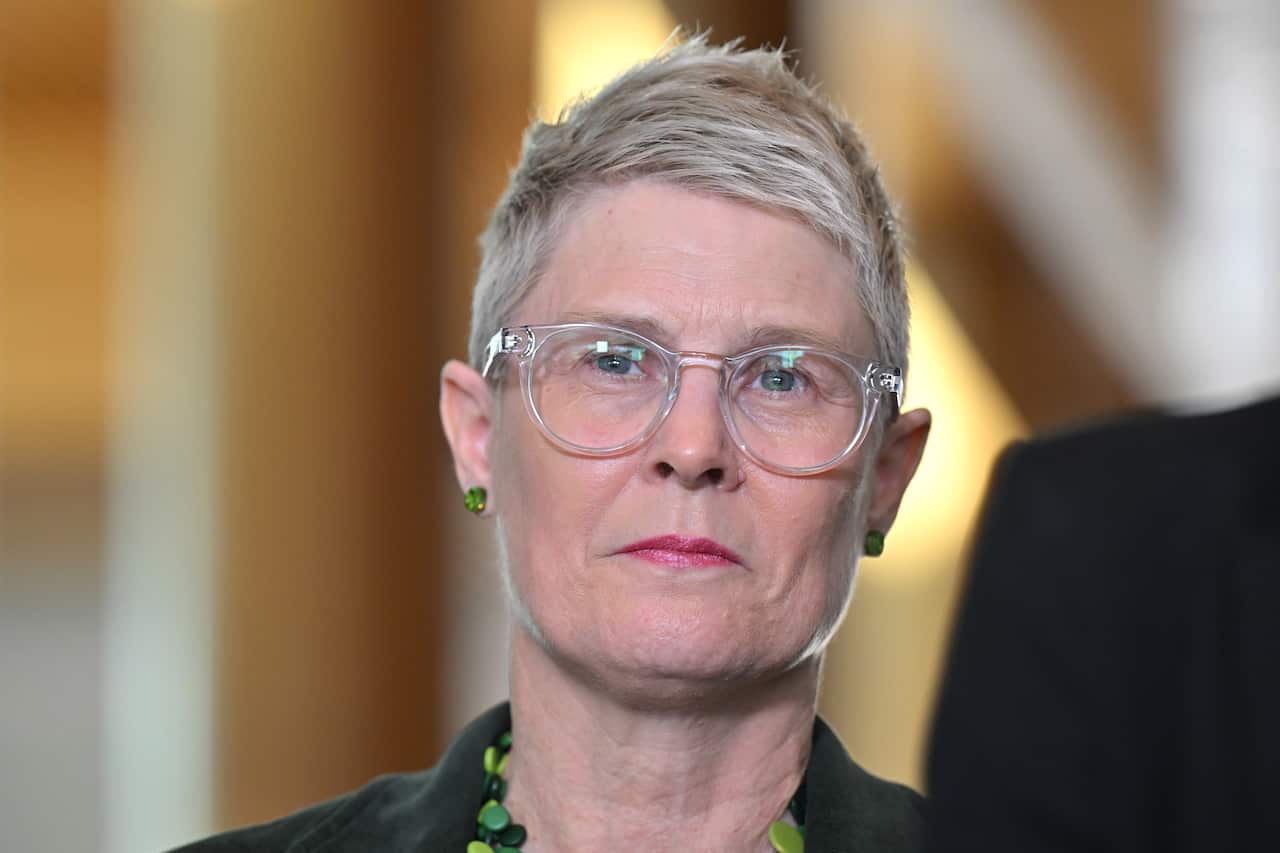 A woman with short bleached hair and transparent glasses