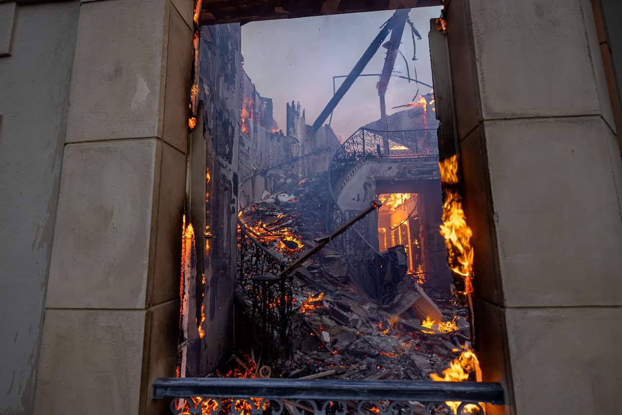  The remains of a staircase burn inside a once palatial home.