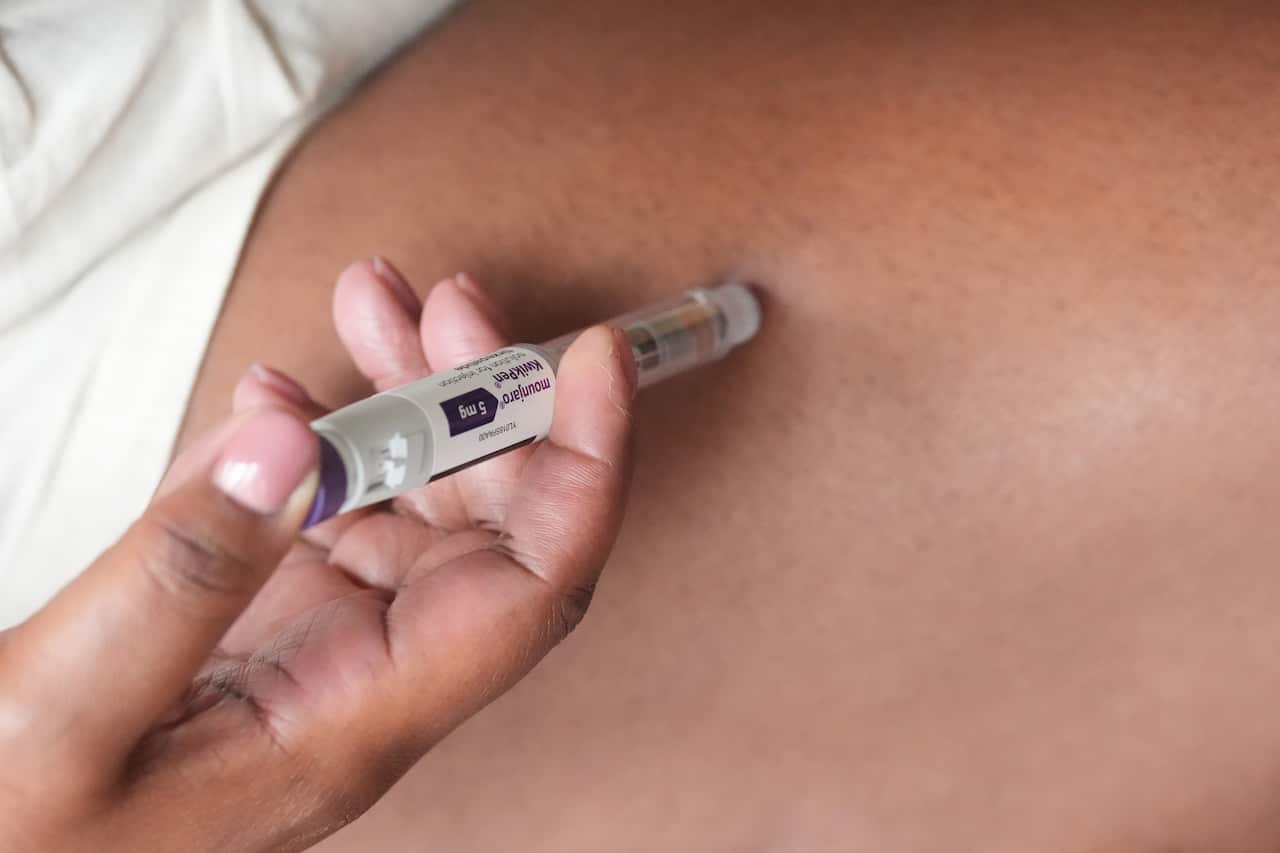 A person is using a pre-filled injection pen on their thigh.