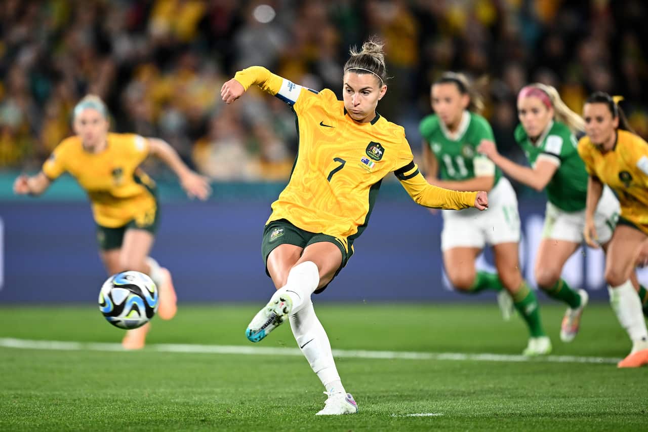 A woman in a yellow football shirt kicks a ball