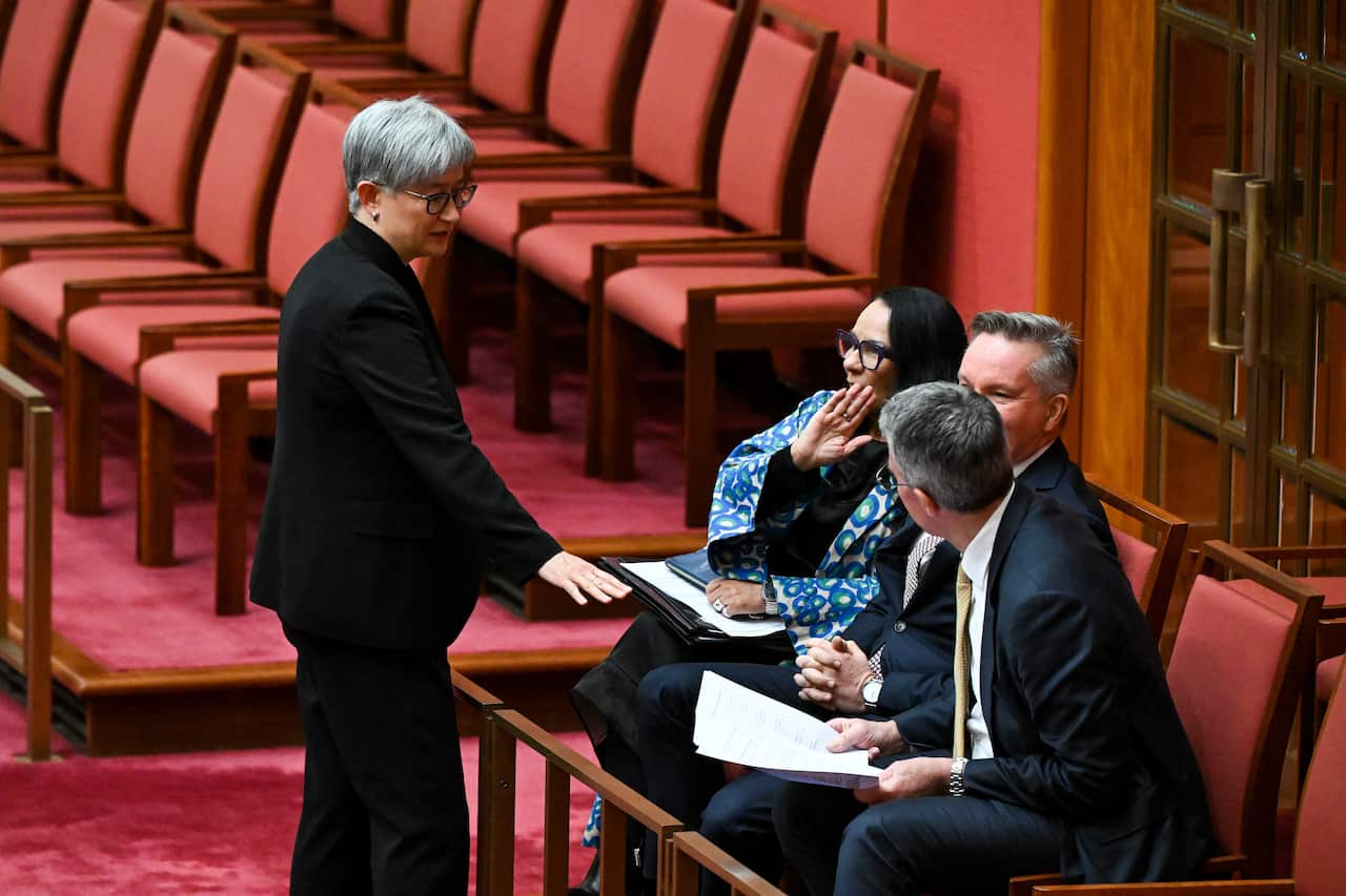 Penny Wong stands in Senate in front of a woman and two men sitting down