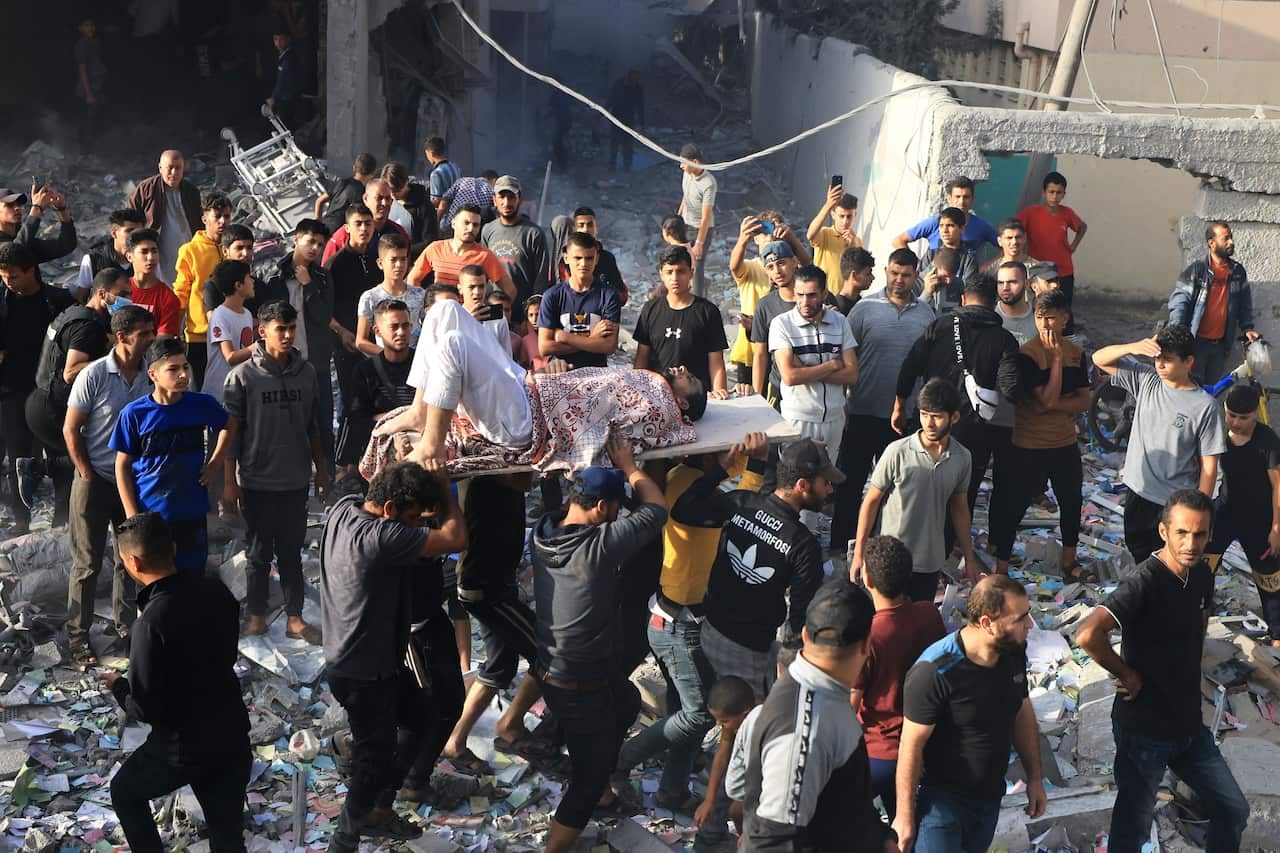 An injured Palestinian is held up on a stretcher among a small crowd of people