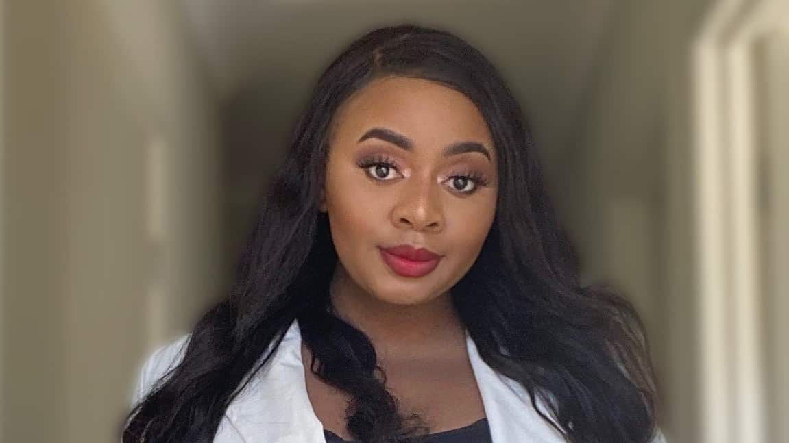 A woman of African descent with long black hair wearing a white blazer 