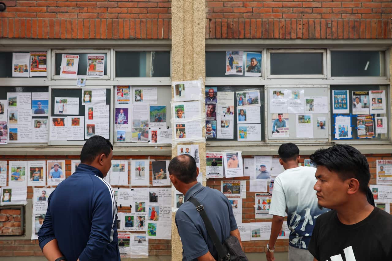 People looking at images of missing people on a wall
