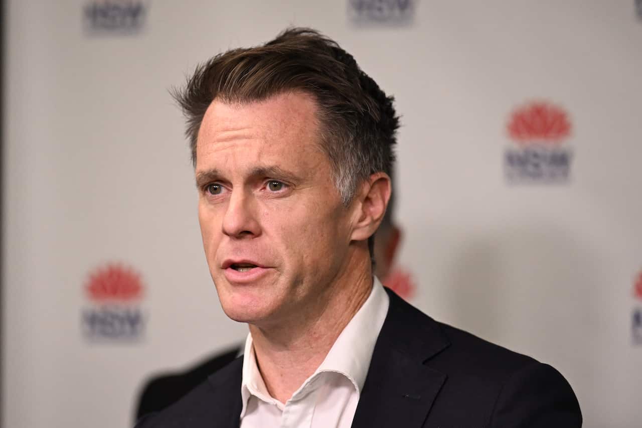Chris Minns standing in front of a background that has the NSW logo.