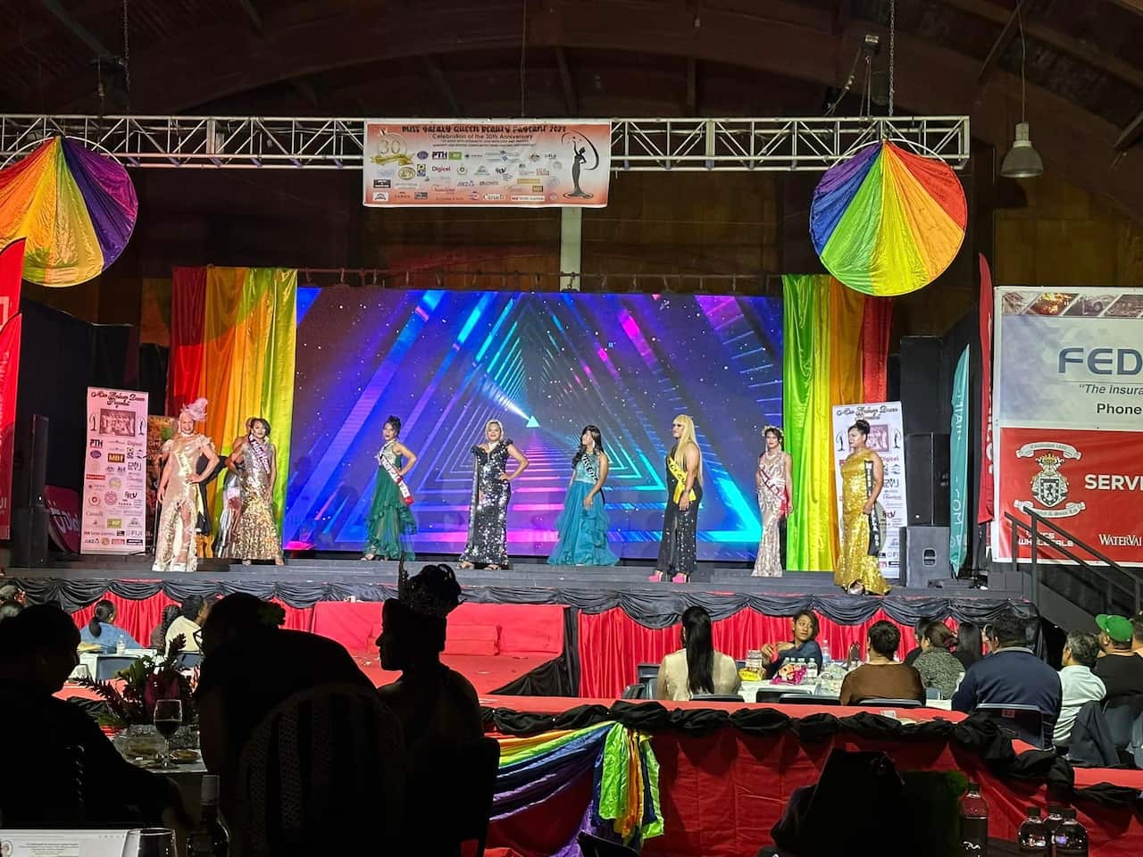 Eight women in ballgowns lined up on stage.