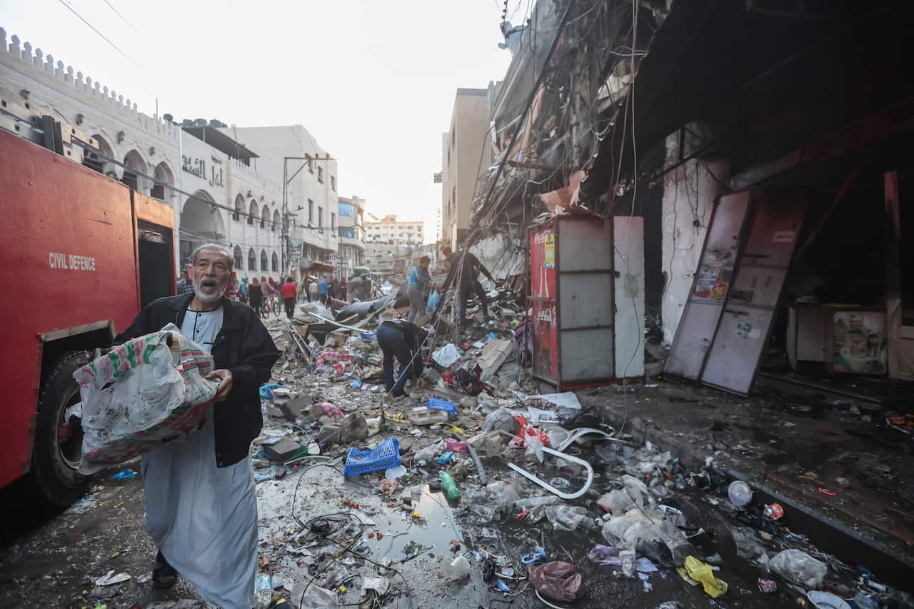 A man walking along a street strewn with debris.
