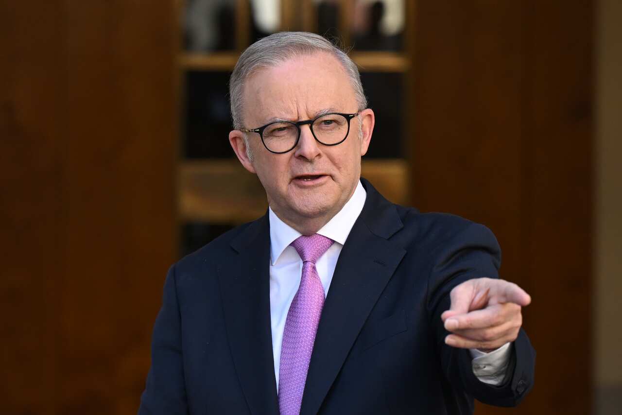Anthony Albanese wearing a suit and a tie points forward with his index finger during a press conference