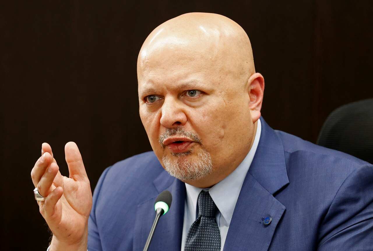 A bald man in a blue suit speaks into a microphone