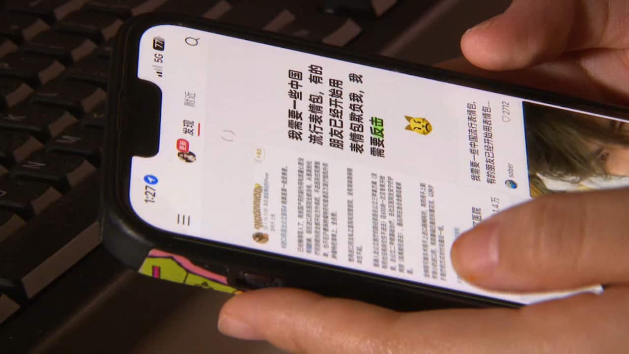 A man holding a phone with a Chinese app on screen