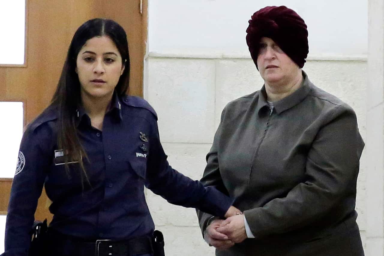 A woman being led into court in handcuffs.