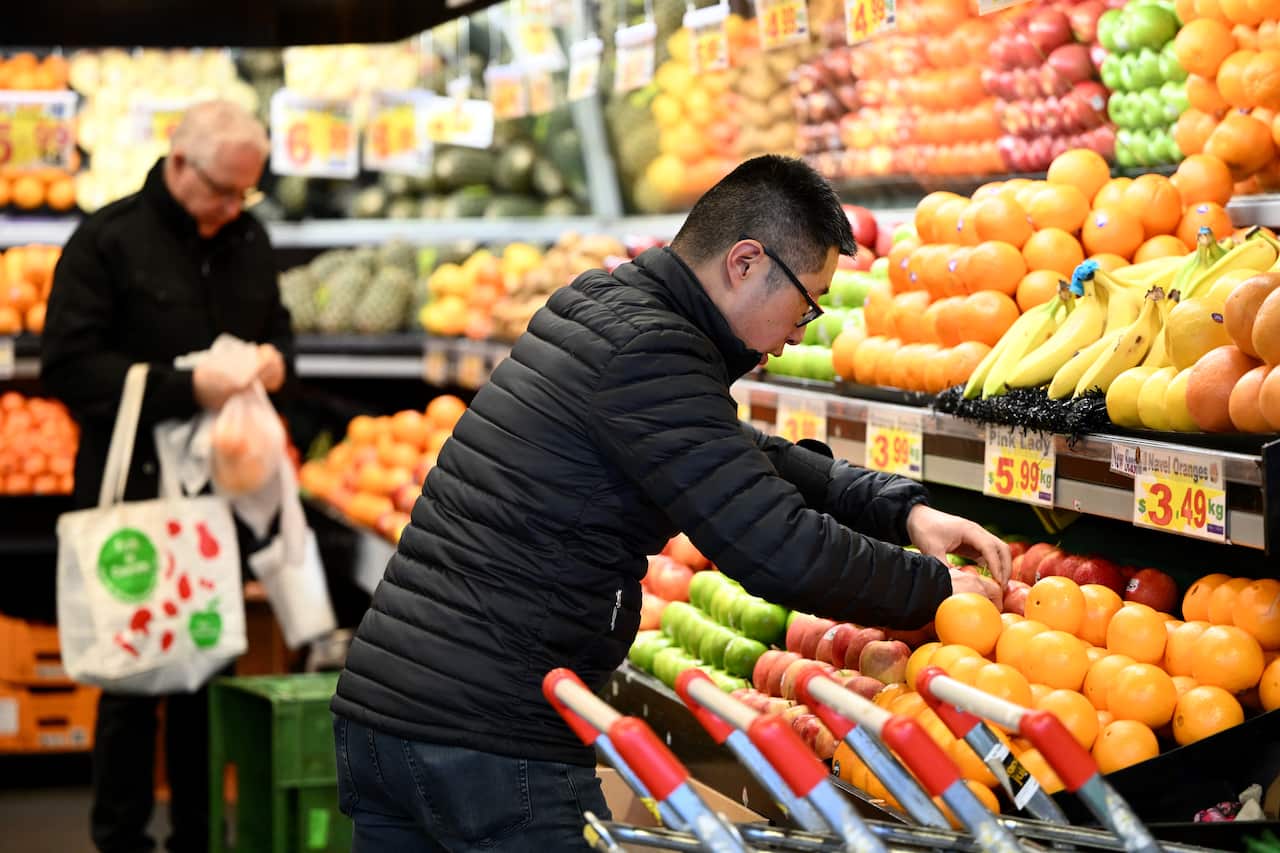 A worker arranges apples for sale at a market in Melbourne.
