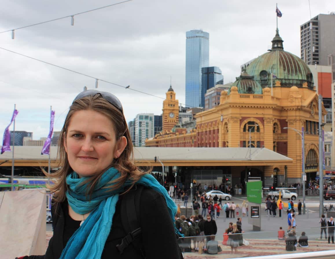 An old picture of a young woman posing for a photograph in front of Melbourne's Flinders Street Station.