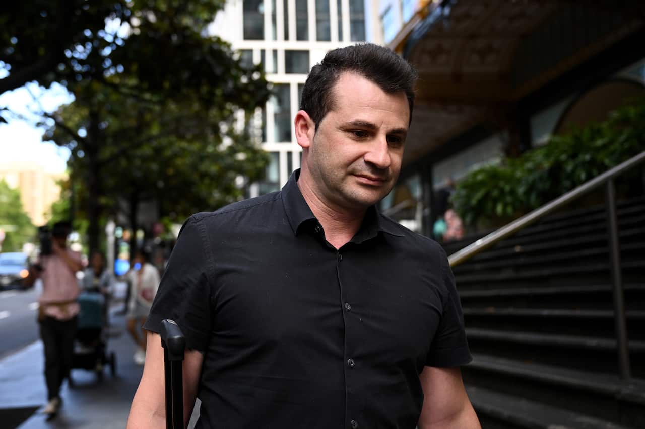 A man in a black shirt walks outside a court.
