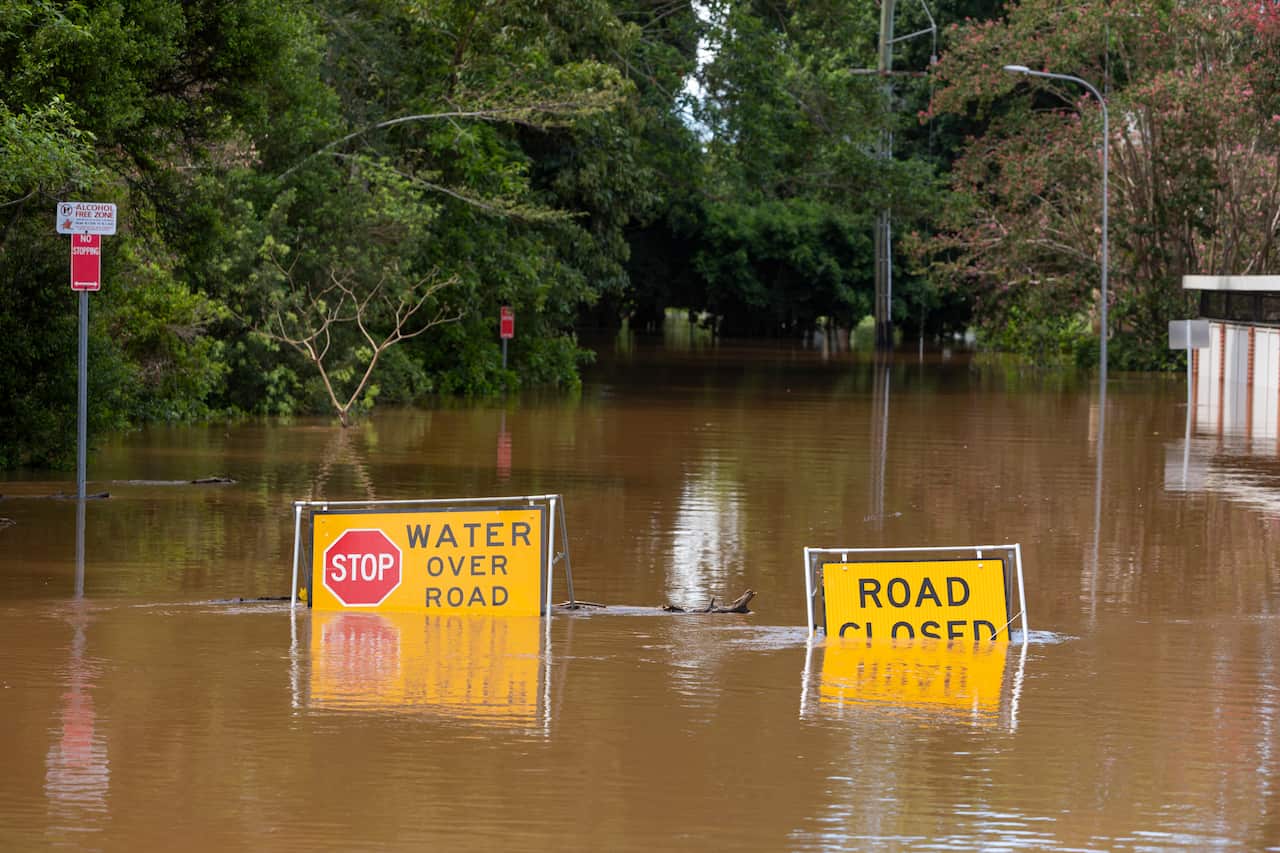 Flood sign under water on road.