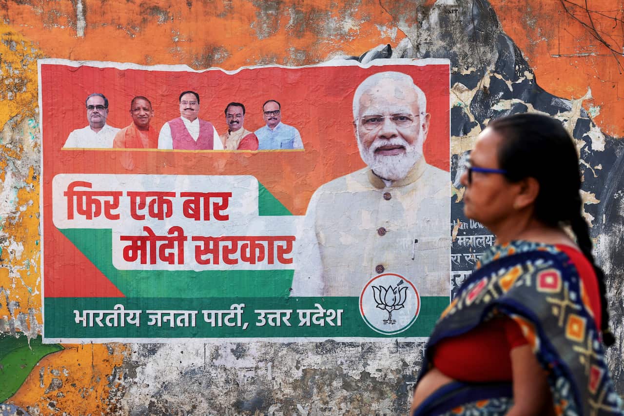 A woman walks past a poster with the face of India's Prime Minister Narendra Modi