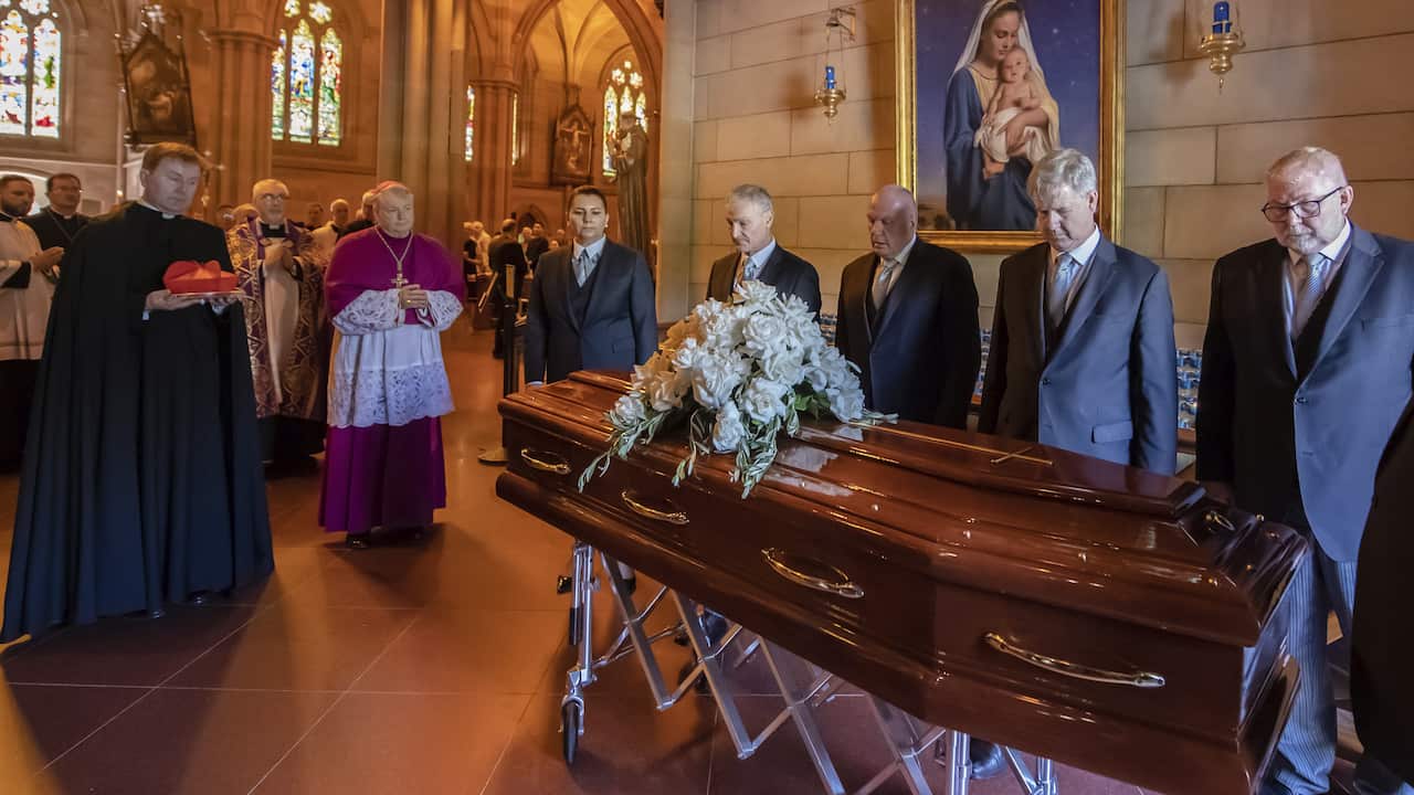 Group of people crowded around a coffin
