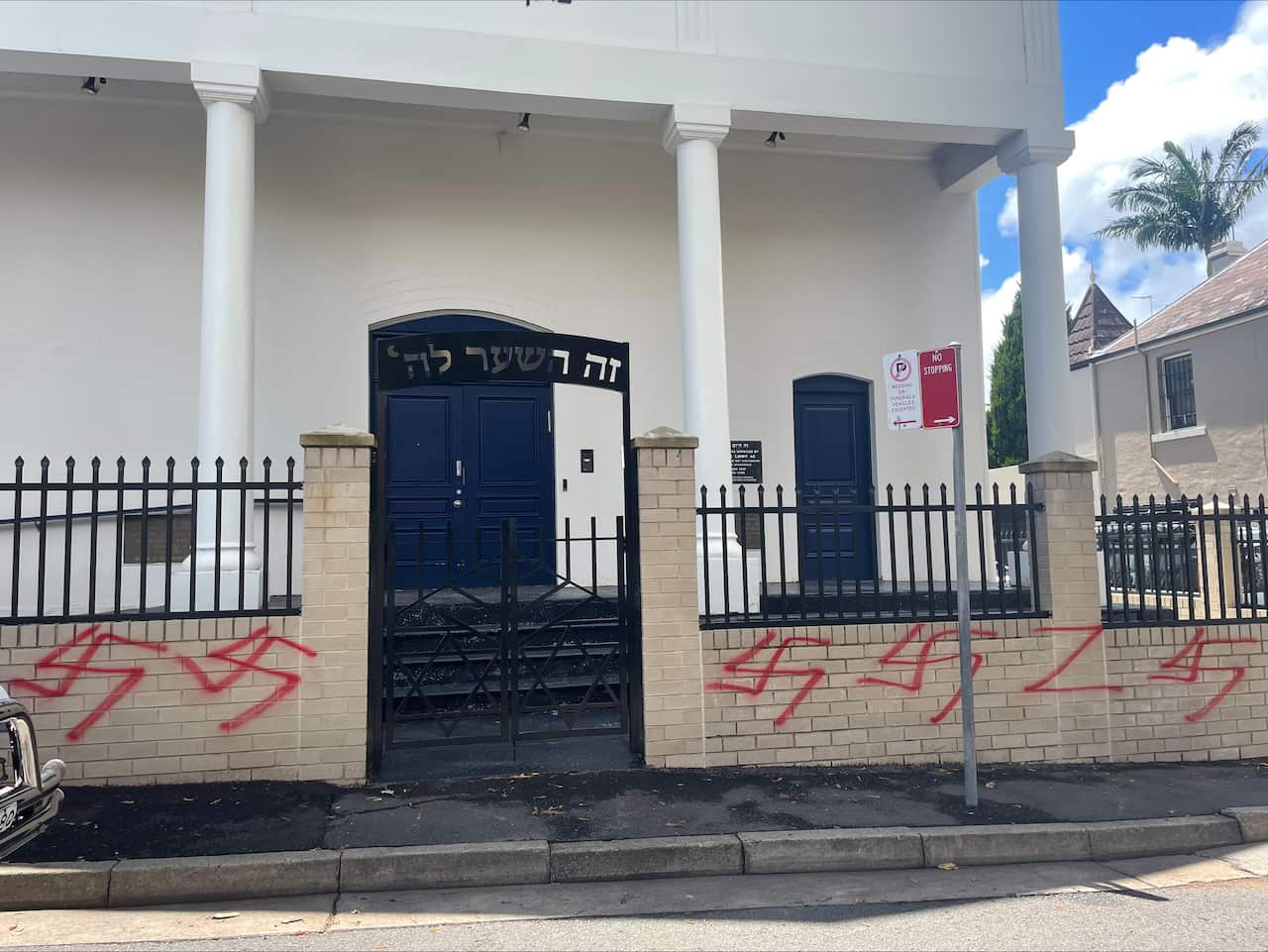 The fence of a synagogue with the red Nazi Hakenkreuz symbol painted in red multiple times.