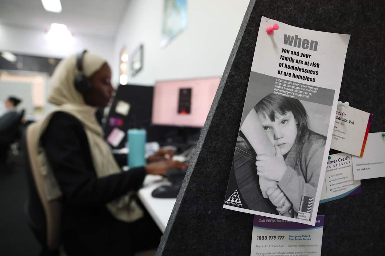 A call taker pictured in the background, with a pamphlet of homelessness in the foreground.