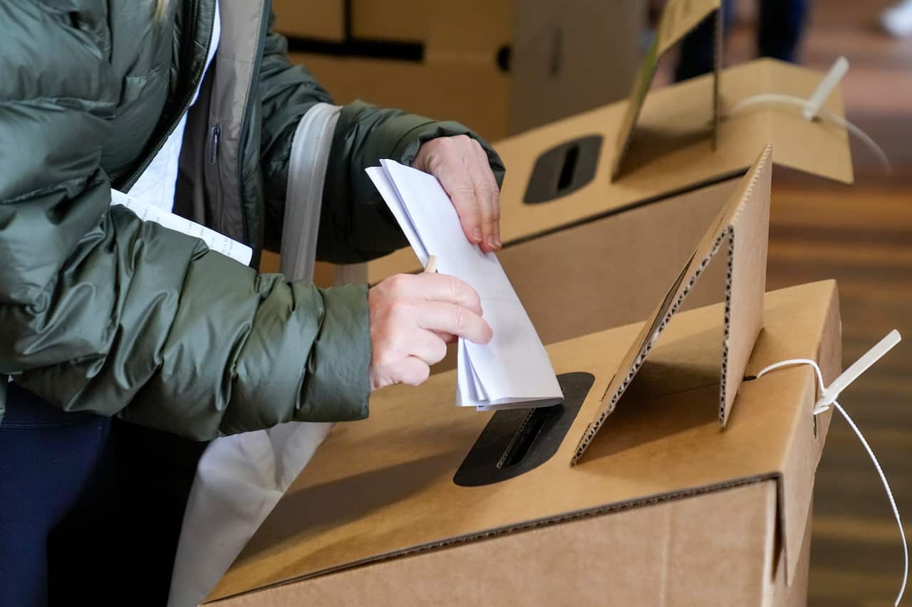 A voter places her ballot paper at a polling booth.