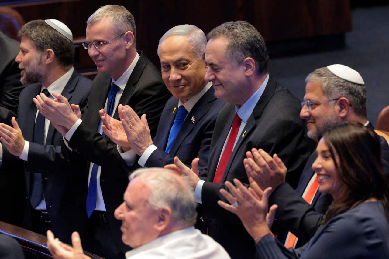 A row of men and a woman in dark suits applauding.