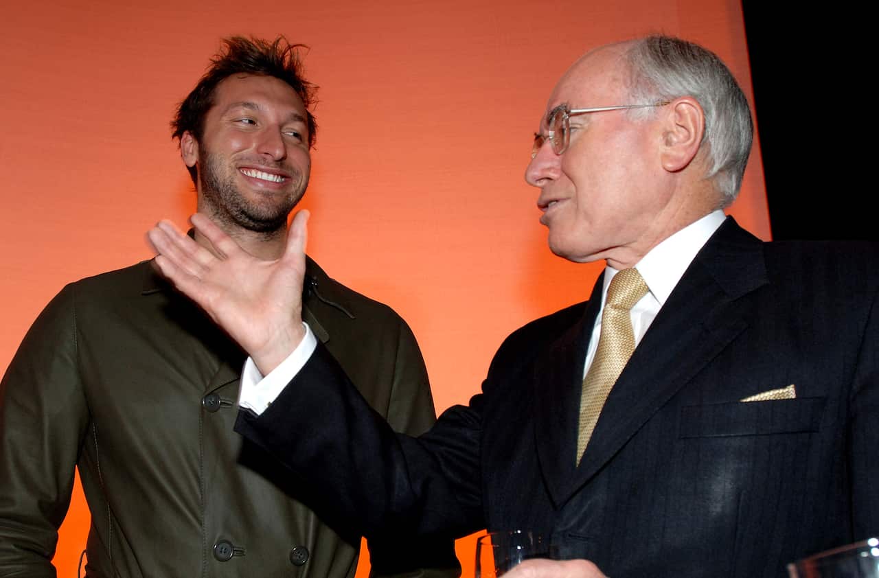 Two men talking, with one gesturing with his hand.