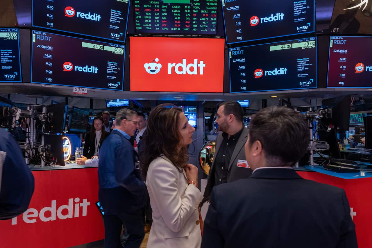 Stockbrokers standing inside looking at screens.